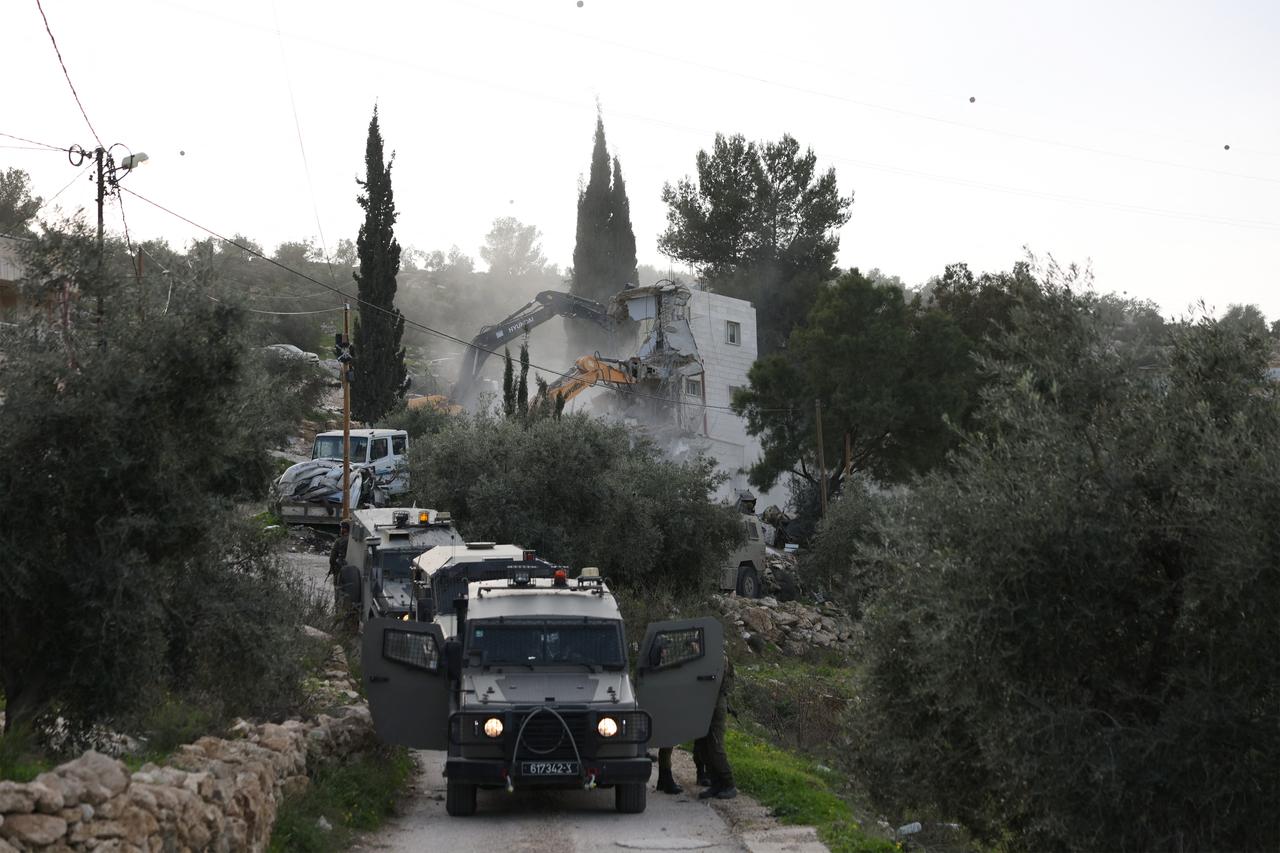 Israeli military vehicles block the road as an Israeli bulldozer demolishes Palestinian-owned homes in the village of Tarqumia, near occupied West Bank city of Hebron, Feb. 1, 2026. (AFP Photo)