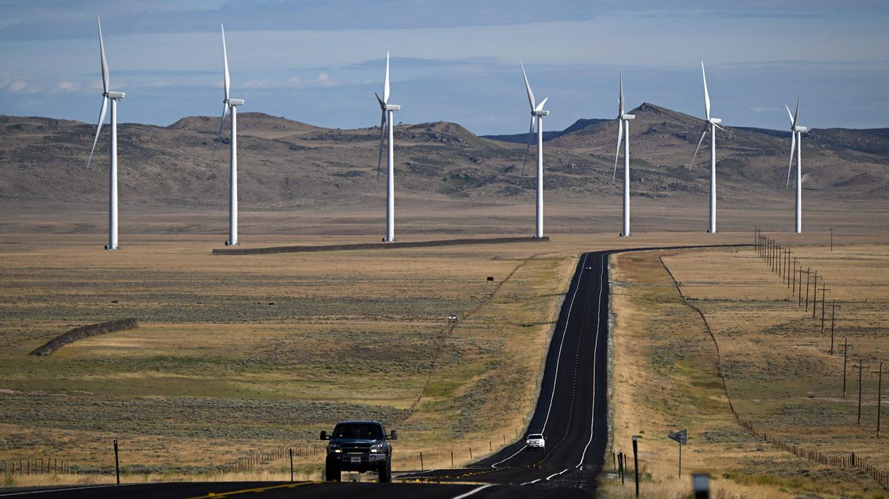 A pickup truck drives on a road as wind electric power generation turbines generate electricity outside Medicine Bow, Wyoming, US on August 14, 2022. (AFP Photo)