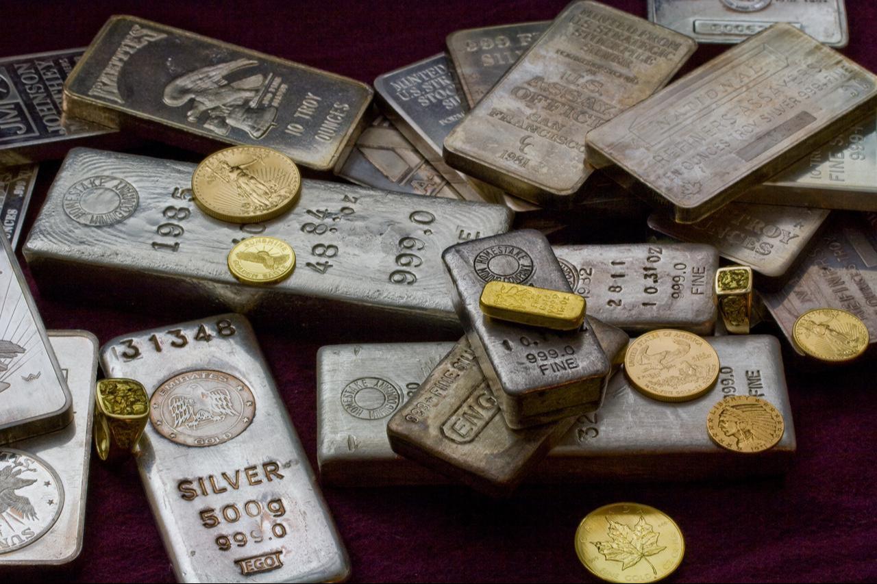 Stacks of gold and silver bullion bars and coins on a dark surface. (Adobe Stock Photo)