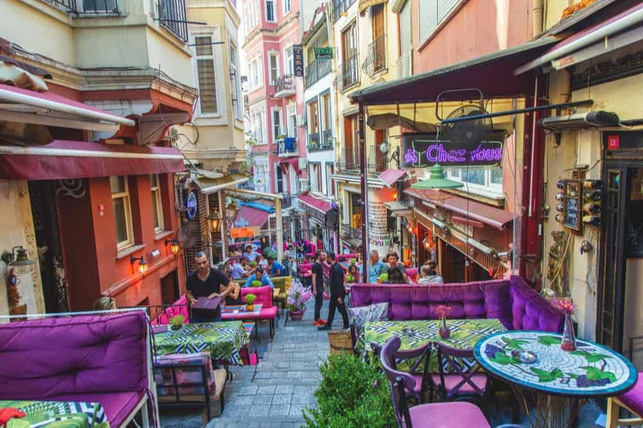 Daytime view of La Rue Francaise in Istanbul, featuring colorful cafes, vibrant buildings, and a stepped street lined with shops, evoking a charming French atmosphere. Source: TheElysiumHotels
