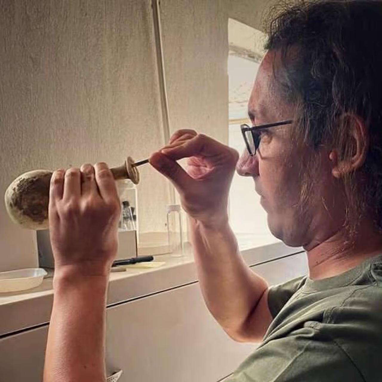 Dr. Ilker Demirbolat inspects the Roman glass vessel analyzed in the archaeological study, Bergama, Türkiye, February 2026. (Courtesy of Cenker Atila)