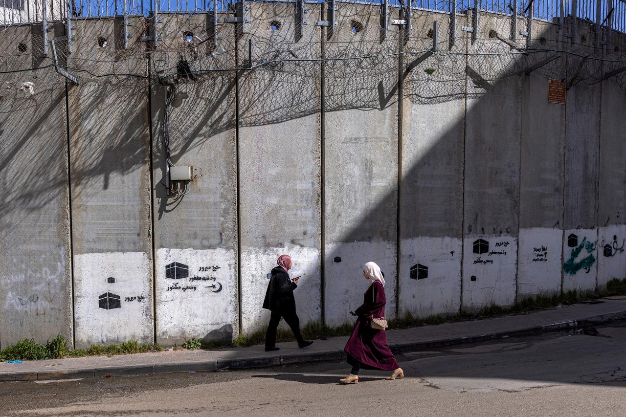Palestinian women walk next to Israel's controversial separation barrier in the Dahiat al-Barit suburb of east Jerusalem, February 15, 2026. (AFP Photo)