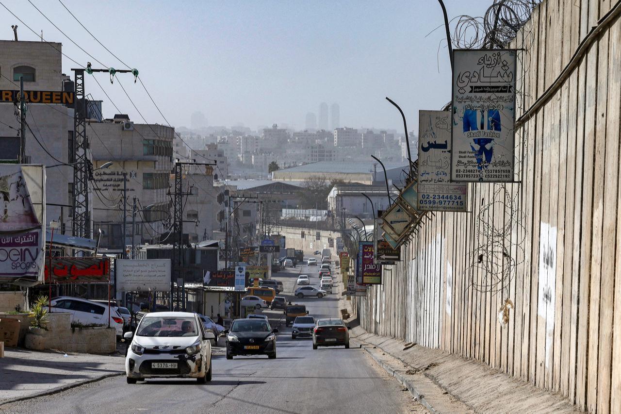 Vehicles move along a road next to Israel's controversial separation barrier in the Palestinian village of al-Ram in the occupied West Bank on February 16, 2026. (AFP Photo)