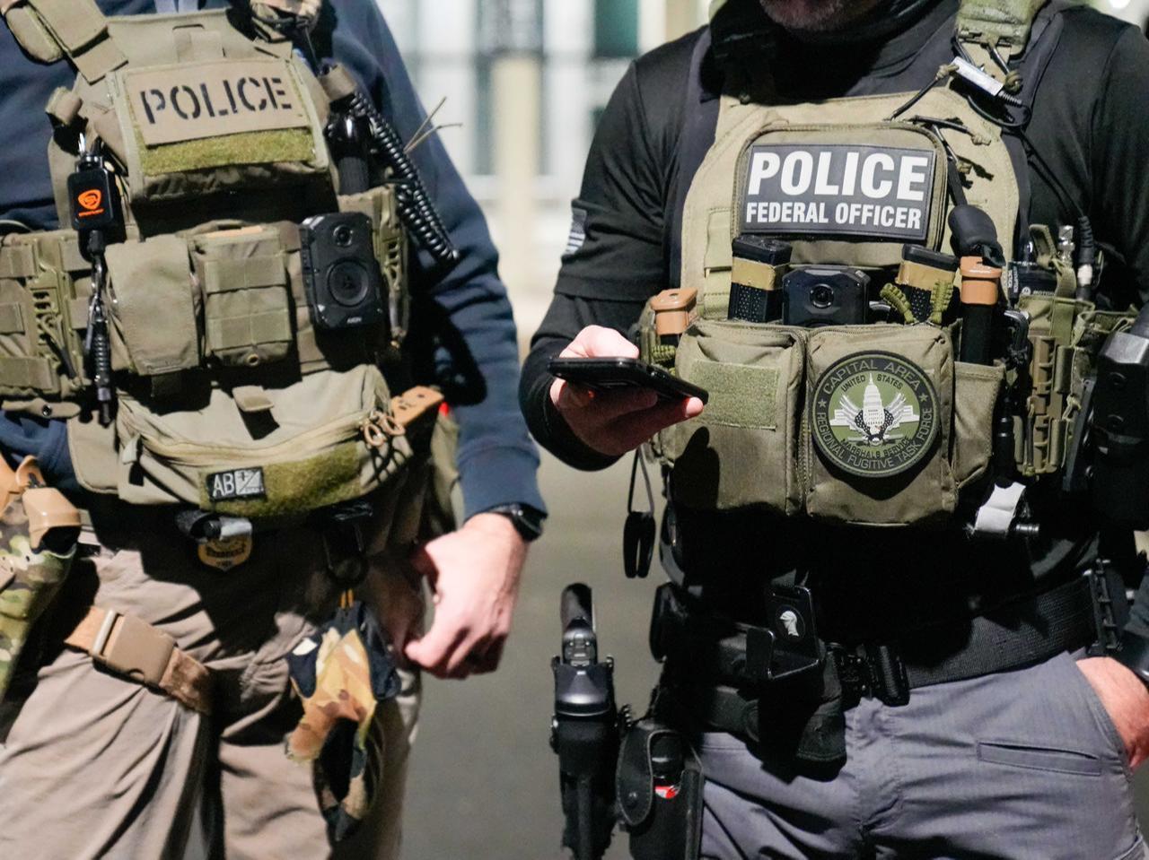 Two federal law enforcement officers coordinate with other officials on the ground, Feb. 4, 2025, near Washington, D.C. (Photo by U.S. Immigration and Customs Enforcement)