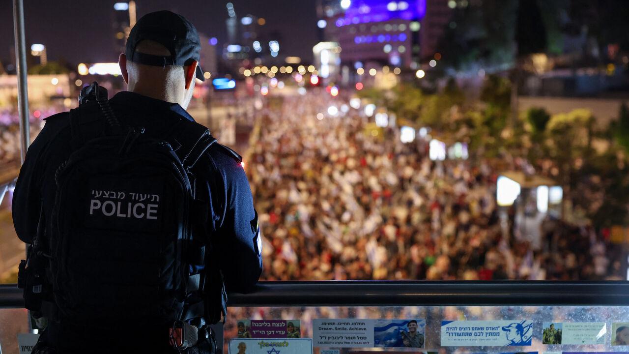An Israeli police man stands guard as relatives and supporters of hostages hold placards and wave national flags during a demonstration calling for their release, in the Israeli coastal city of Tel Aviv, May 4, 2024. (AFP Photo)