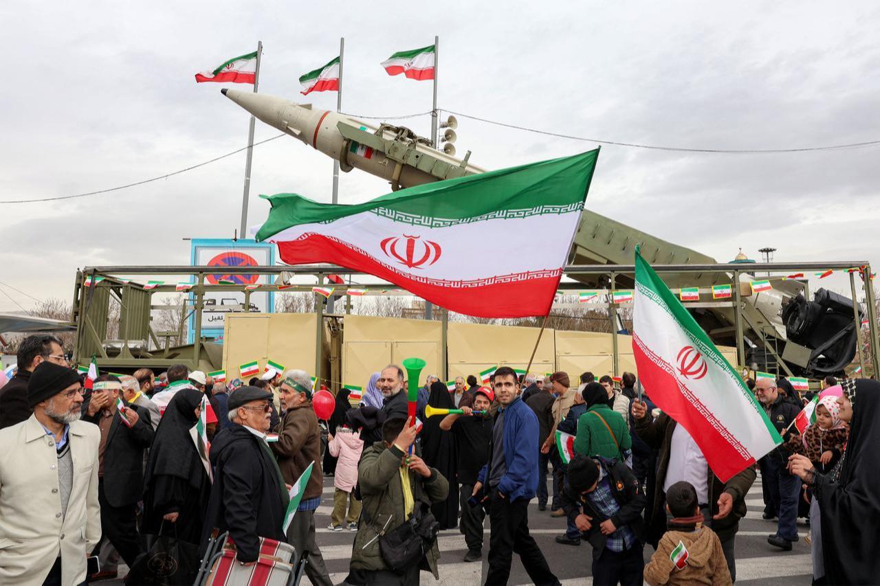 People hold Iranian national flags near a ballistic missile launch vehicle during a rally in Tehran on February 11, 2026. (AFP Photo)
