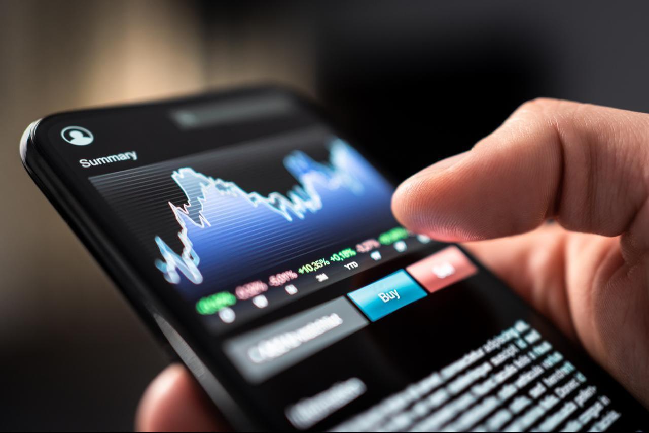 A person uses a mobile trading application. (Adobe Stock Photo)