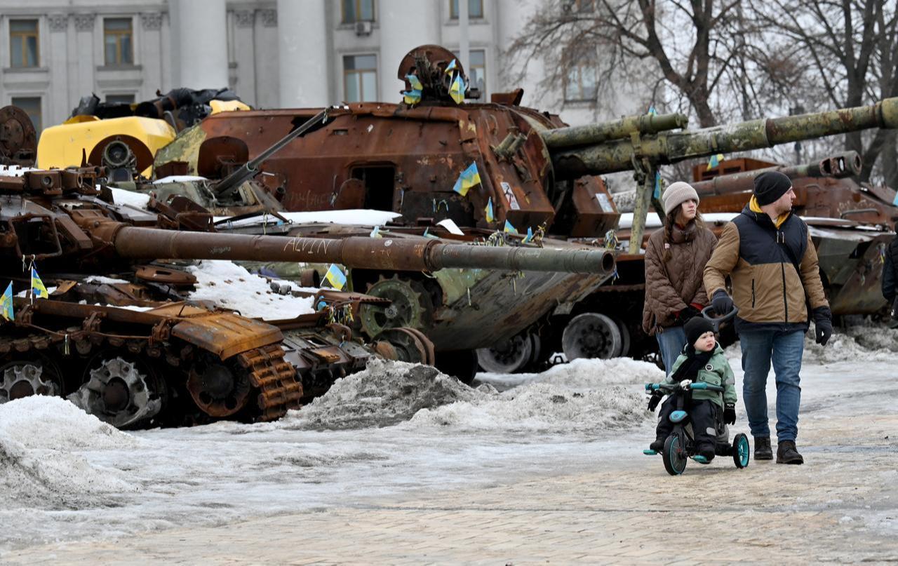 A couple and a boy on a bicycle walk in the open-air exhibition of destroyed Russian military equipment in Kyiv, February 15, 2026. (AFP Photo)