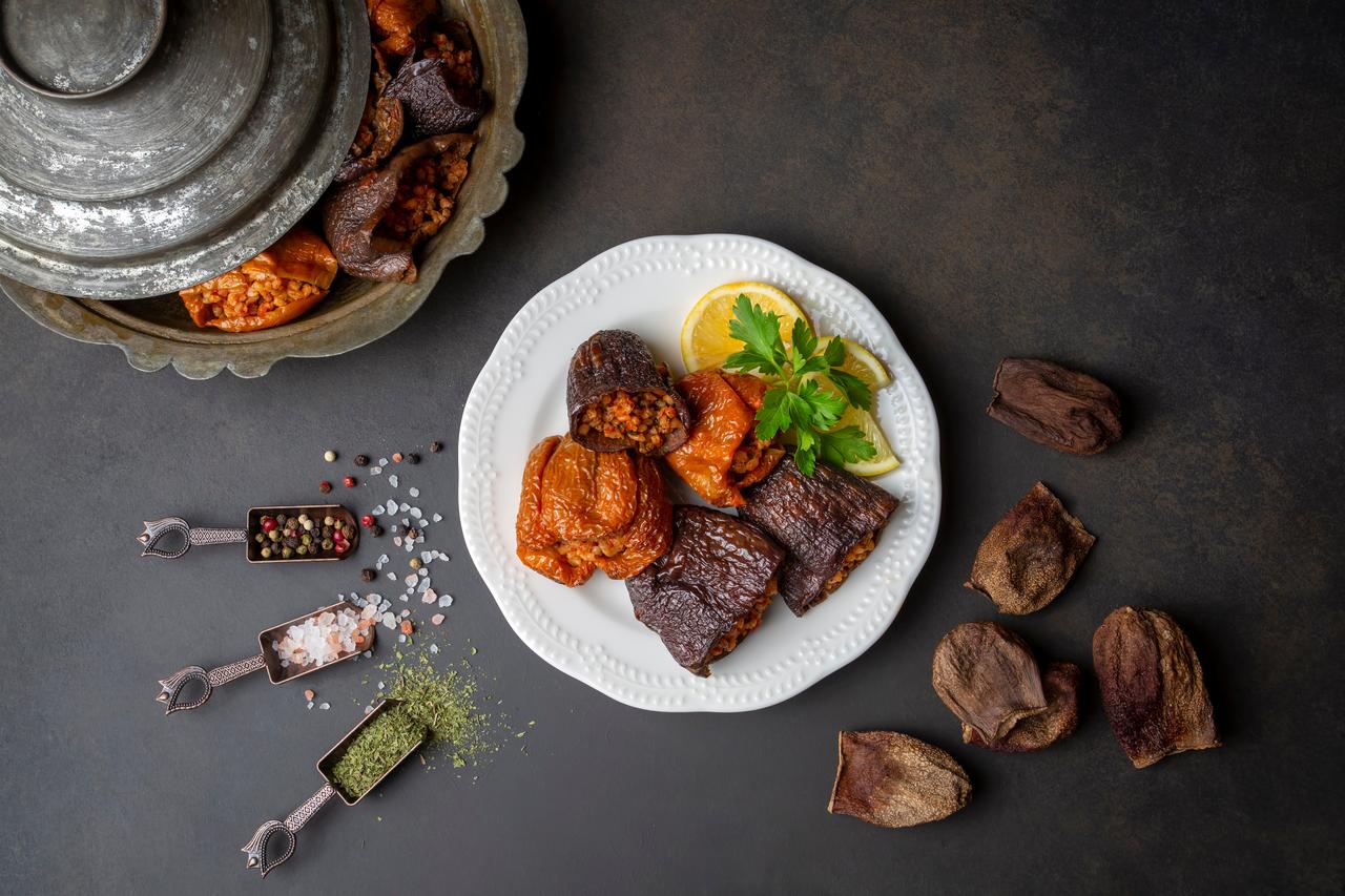 A mixed plate of stuffed vegetables including vine leaf rolls and stuffed eggplant, illustrating the diversity of traditional dolma varieties prepared across Türkiye. (Adobe Stock Photo)