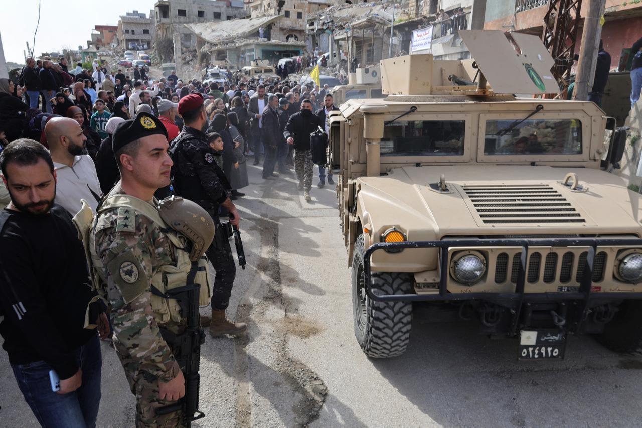 Lebanese army vehicles secure the street as residents gather during a visit by Lebanon's prime minister to the heavily-damaged southern village of Kfar Kila, near the border with Israel, Feb. 8, 2026. (AFP Photo)