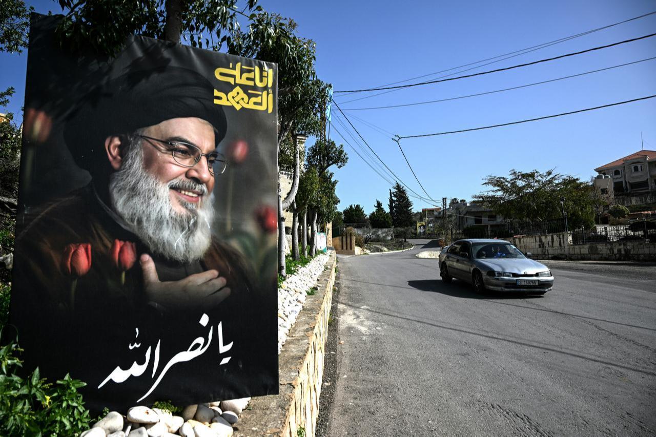A car drives past a poster of slain Lebanese Hezbollah longtime leader Hassan Nasrallah at the entrance of the southern village of Qannarit, February 16, 2026. (AFP Photo)