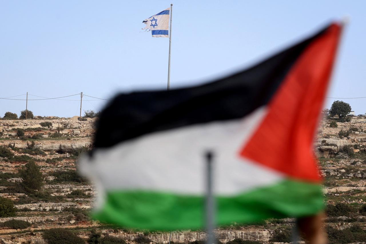This picture taken from Umm Safa village, north of Ramallah in the occupied West Bank, shows a Palestinian flag (foreground) and Israeli flag fluttering on a hilltop overlooking the village on February 16, 2026. (AFP Photo)