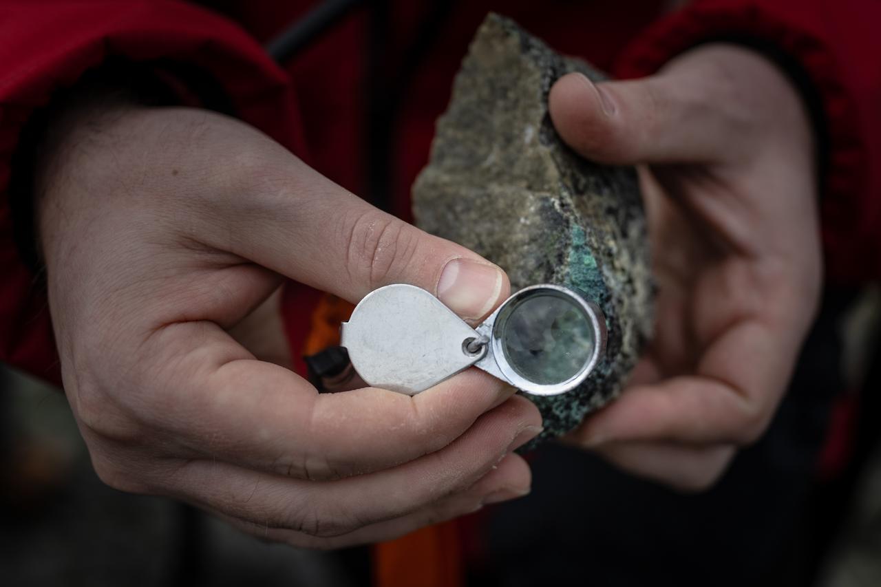 A geologist inspects a rock sample with a hand lens during field analysis conducted under harsh Antarctic conditions. (AA Photo)