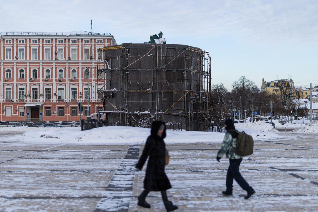 People walk past the Bohdan Khmelnytsky monument covered in protective hoarding, in Kyiv, February 17, 2026. (AFP Photo)