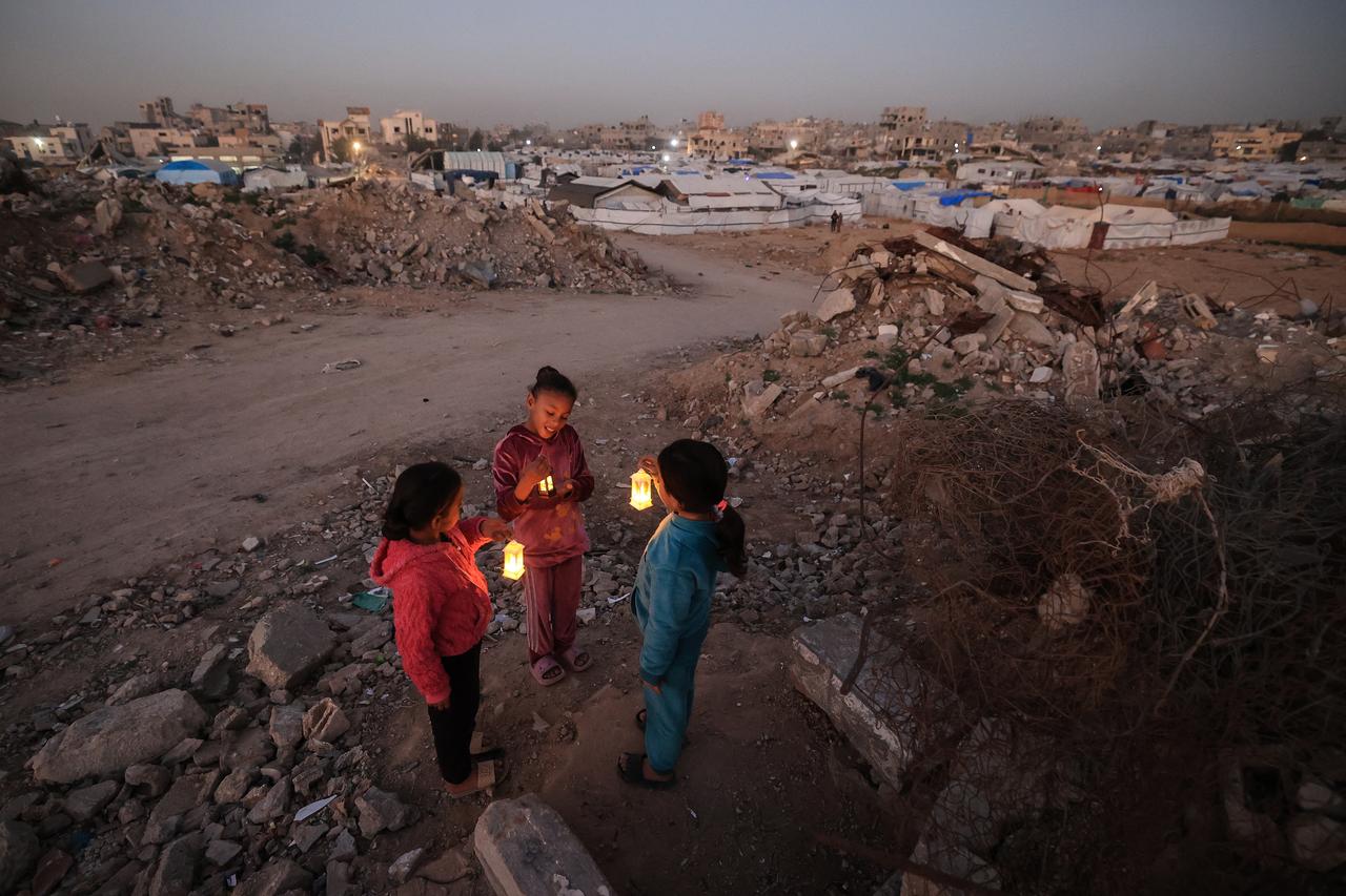 Young displaced Palestinians play on the ruins of destroyed buildings, carrying Ramadan lanterns used as decorations, in the Bureij refugee camp in the central Gaza Strip on February 15, 2026. (AFP Photo)