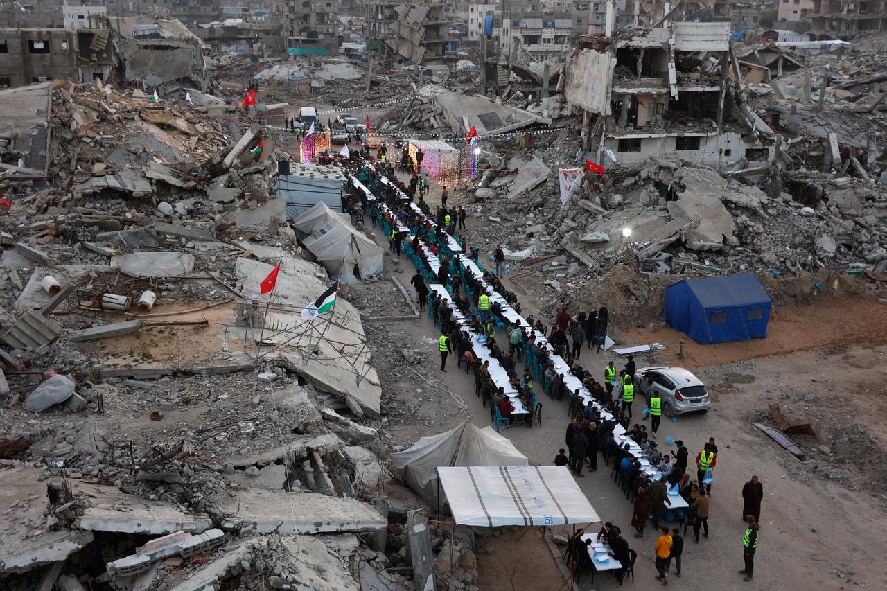 Palestinians gather for a mass fast-breaking iftar meal organized by the Turkish IHH Foundation, amid the rubble of destroyed buildings in Gaza City on February 18, 2026. (AFP Photo)