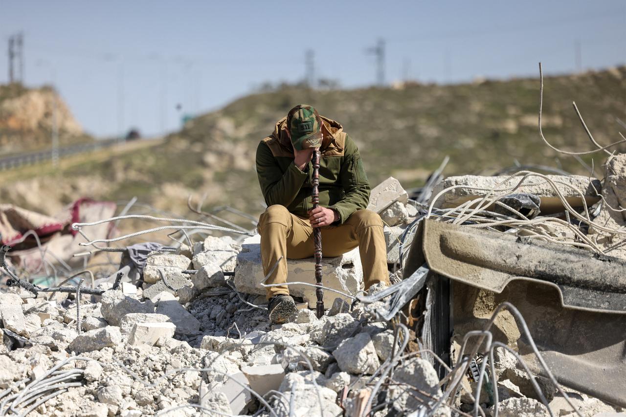 A member of the Salhab family weeps as he sits on the on the rubble of apartment building after it was demolished by Israeli bulldozers near the Israeli settlement of Hagai, south of the occupied West Bank city of Hebron, on Feb. 18, 2026. (AFP Photo)