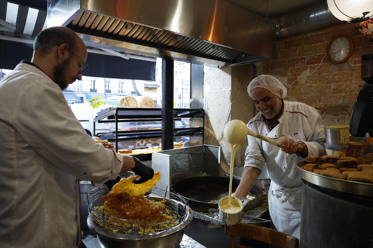 A vendor makes Zlabia delicacies in his shop before the start of the holy month of Ramadan in the Belleville district of Paris on February 17, 2026. (AFP Photo)