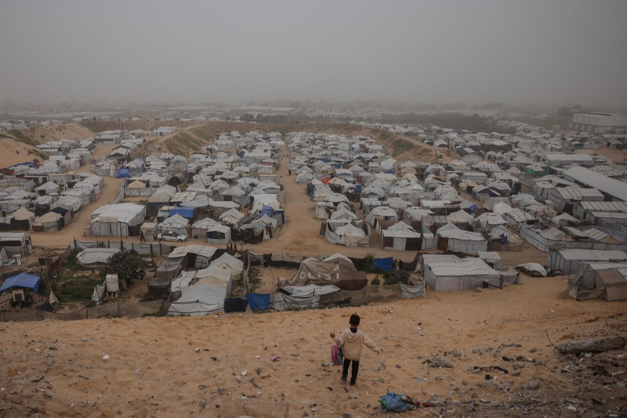 A child walks down a hill overlooking a camp for displaced Palestinians during hazy and dusty weather in Khan Yunis, in the southern Gaza Strip, on Feb. 14, 2026. (AFP Photo)