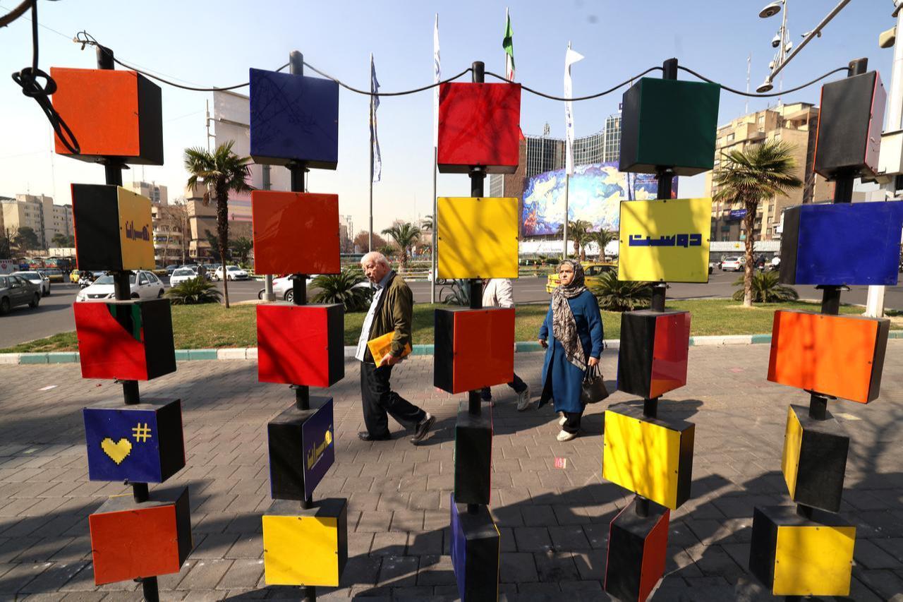 Iranians walk past a Graphite cubes erected in Valiasr Square in Tehran, on February 22, 2026. (AFP Photo)