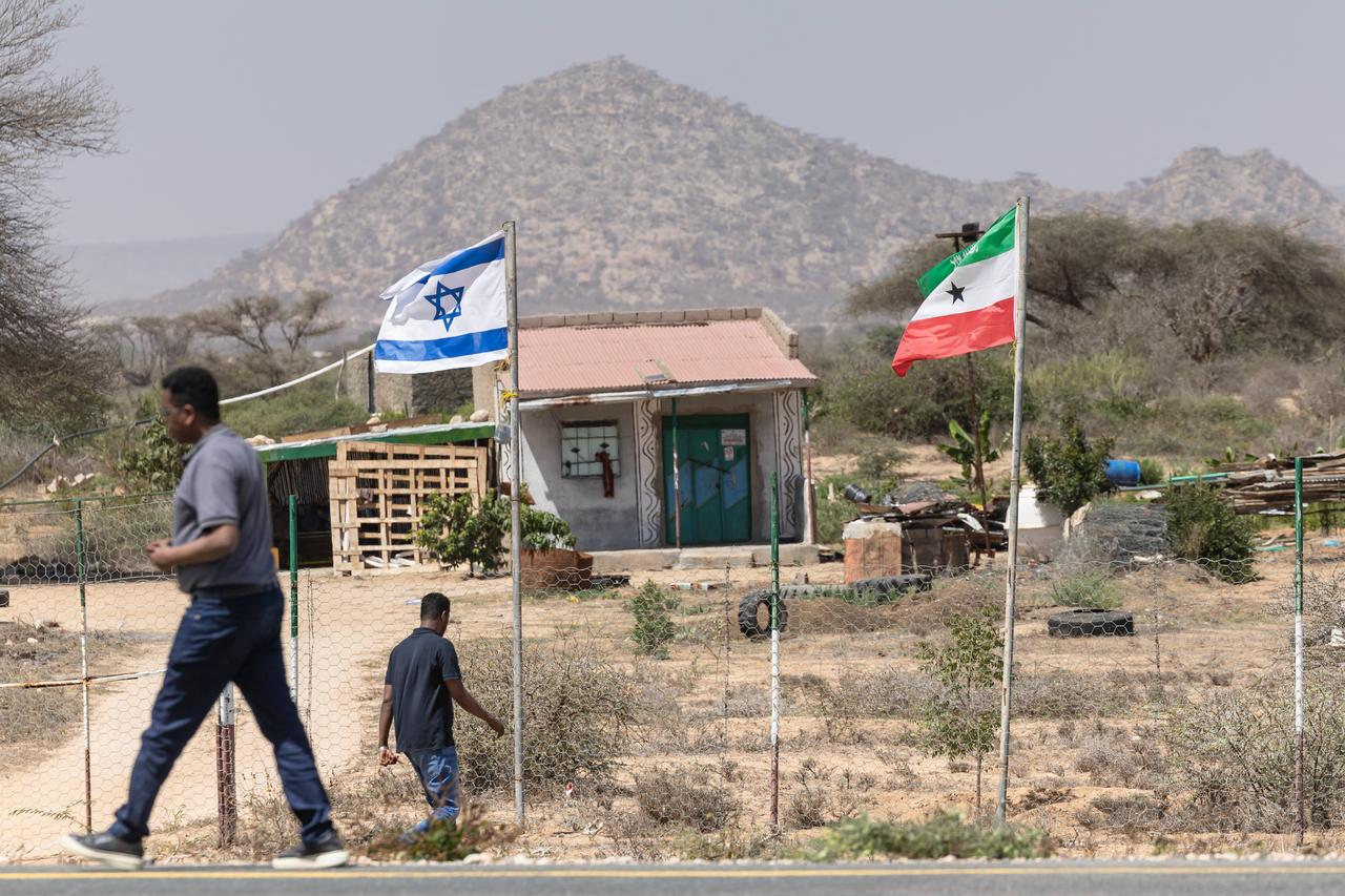 People walk by the flags of Israel and Somaliland flying alongside each other at the entrance to a fruit farm between the capital city of Hargeisa and Port city of Berbera along the highway connecting the two as Muslims commemorate the holy month of Ramdhan in Somaliland on February 19, 2026. (AFP Photo)