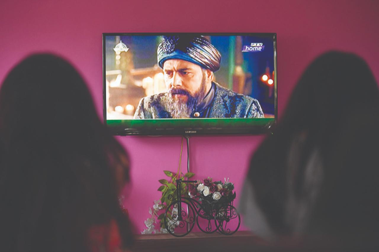 A family watches Turkish drama series "Dirilis: Ertugrul" telecast on Pakistan's state-run channel PTV Home during the holy month of Ramadan, May 9, 2020. (AFP Photo)