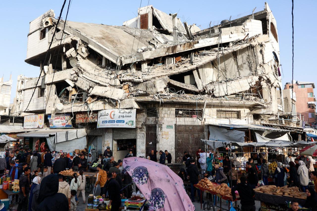 Palestinians shop for food beneath a destroyed building in Gaza City's Zawiya market on Feb. 18, 2026. (AFP Photo)