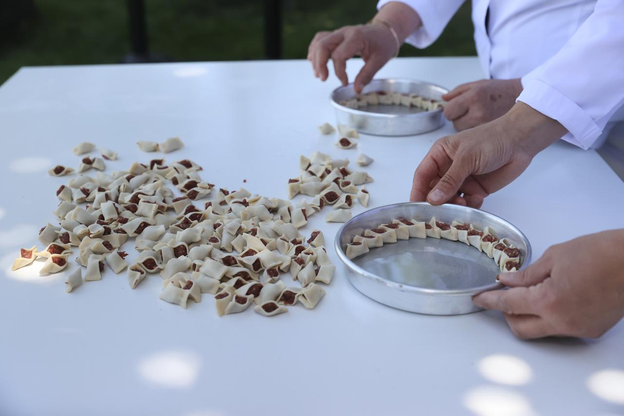 Hand-folded dumplings are carefully arranged in a baking tray while preparing tepsi mantisi in Kayseri, Türkiye, Feb. 22, 2026. (AA Photo)