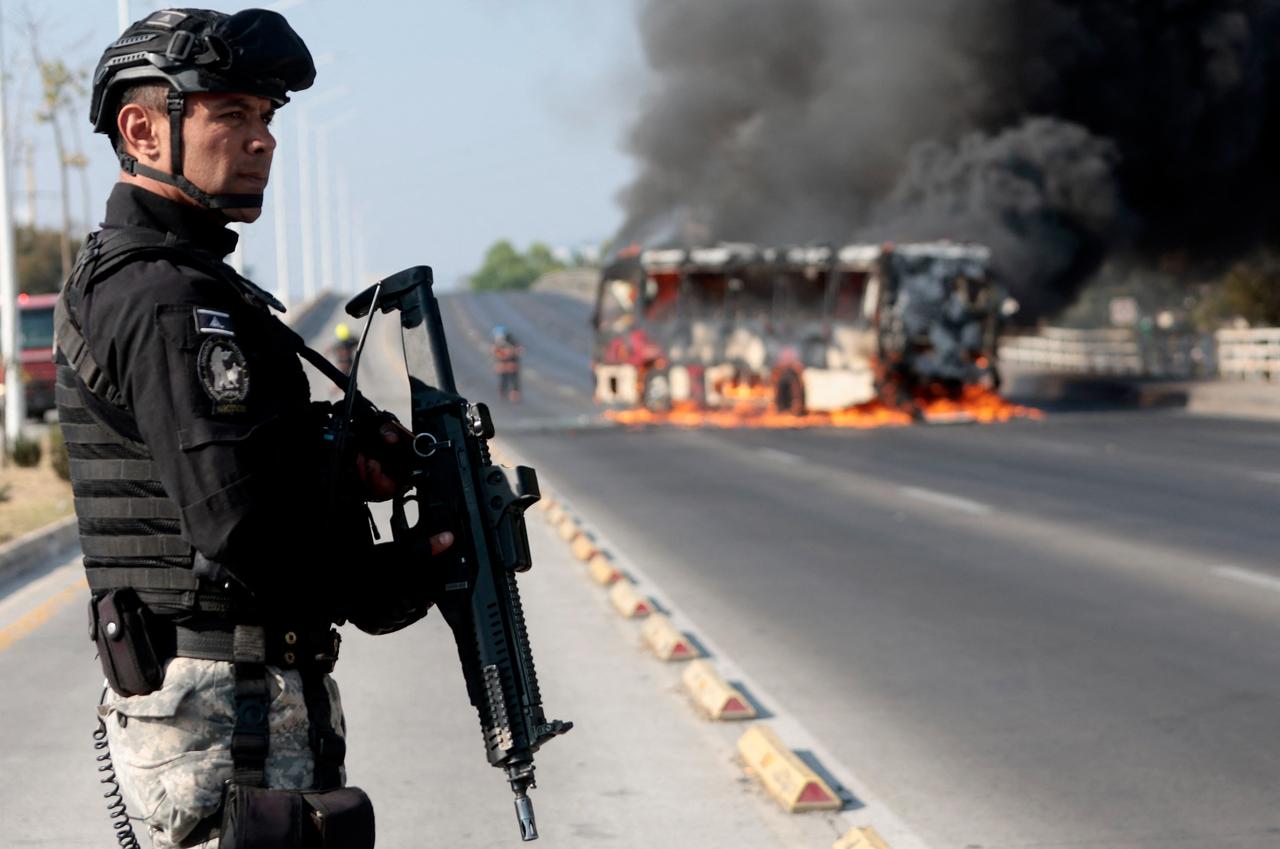 A member of the Prosecutor's Office stands guard near a burning bus at one of the main avenues after it was set on fire in Zapopan, state of Jalisco, Mexico, Feb. 22, 2026. (AFP Photo)