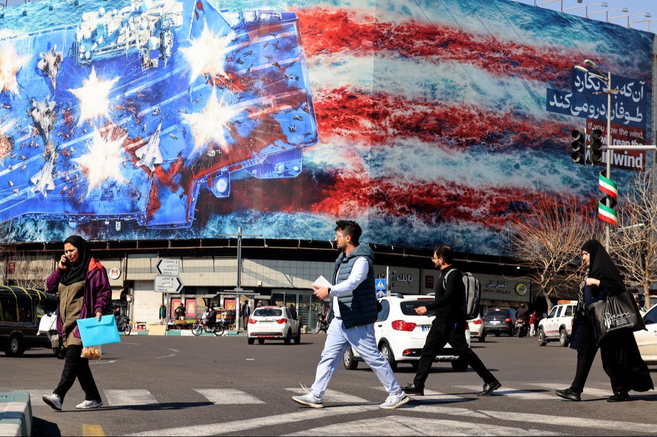 Iranians walk past an anti-US billboard installed on a building on Enqelab Square in Tehran, February 17, 2026. (AFP Photo)