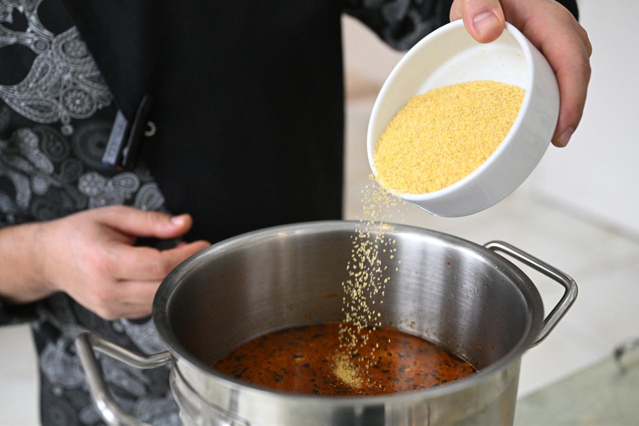 Finely cracked wheat is added to a simmering pot while preparing traditional wedding soup in Kayseri, Türkiye, Feb. 24, 2026. (AA Photo)