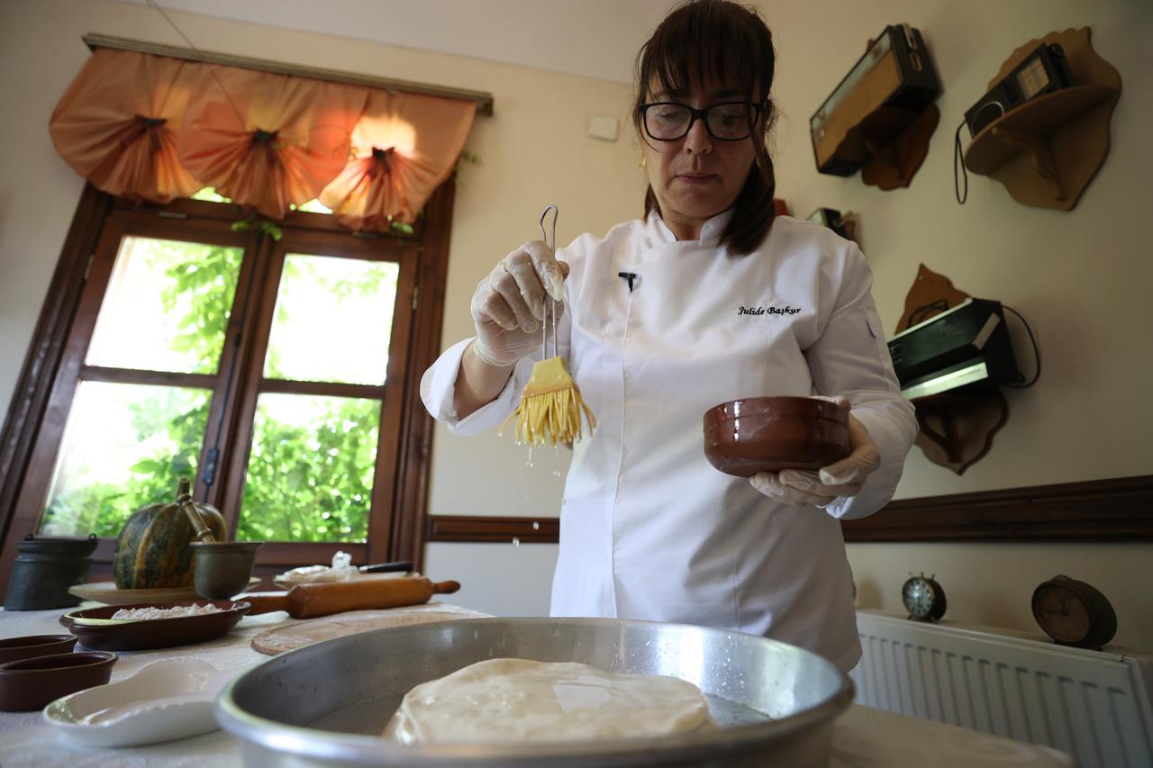 Chef Julide Baskur brushes dough layers with oil while preparing tikvenik pastry in Kirklareli, Türkiye, Feb. 25, 2026. (AA Photo)
