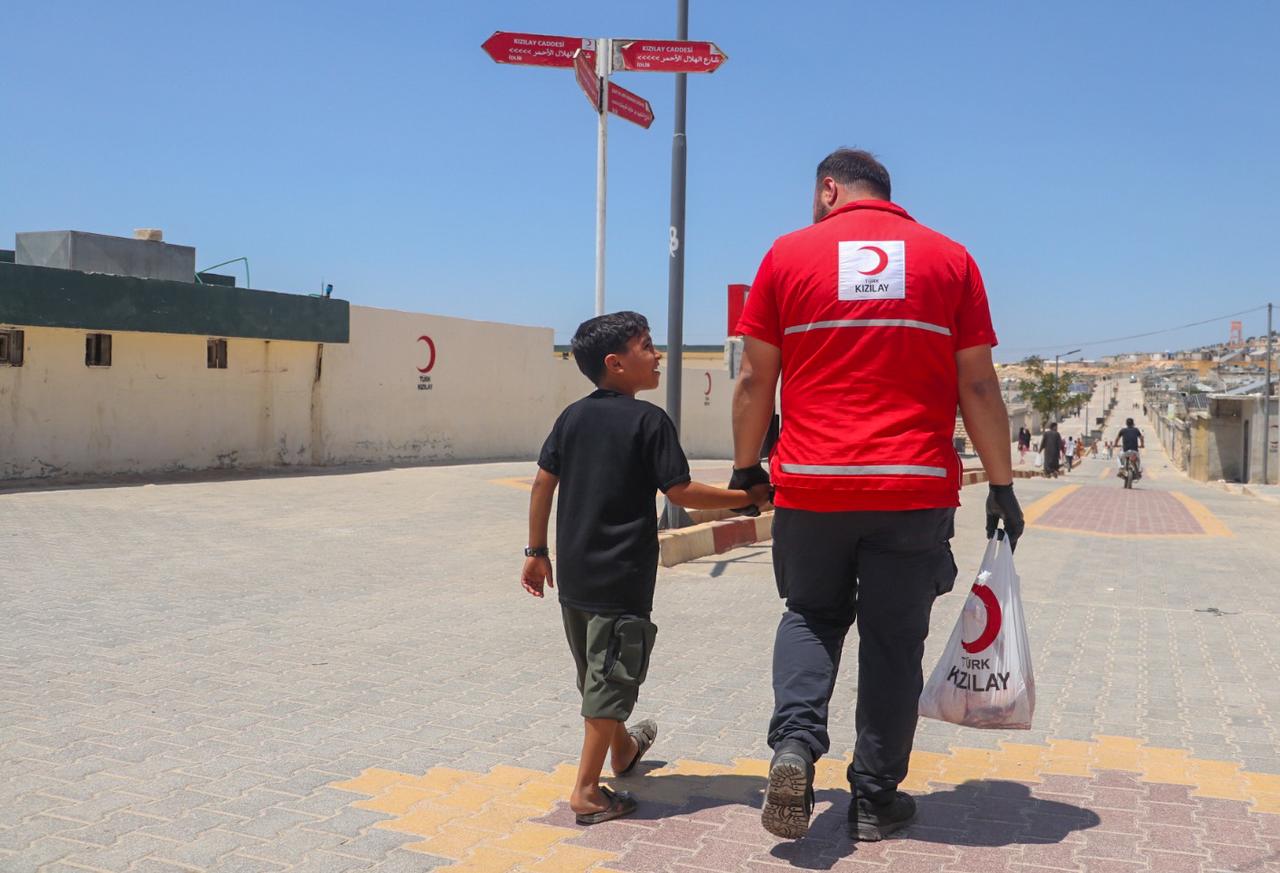 A Turkish Red Crescent worker holds the hand of a Syrian child in northern Syria. (Photo: Red Crescent)