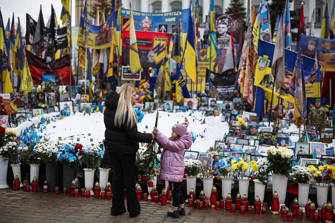 A woman and child visit a makeshift memorial for Ukrainian and foreign soldiers in Independence Square in Kyiv on February 24, 2026, on the fourth anniversary of Russia’s invasion of Ukraine. (AFP Photo)