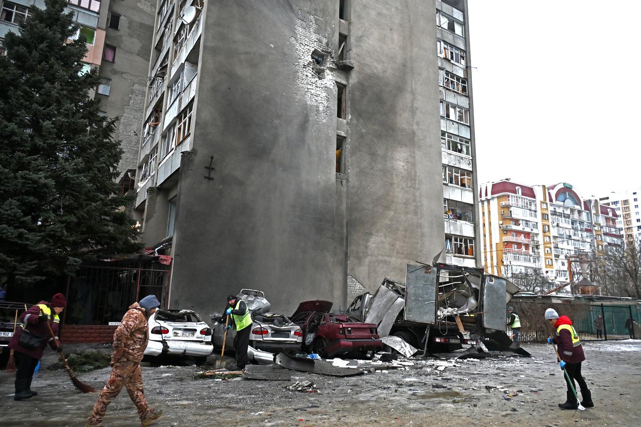 Communal workers clear debris next to destroyed cars in the courtyard of a damaged residential building following an air attack in Kharkiv, Ukraine on February 26, 2026. (AFP Photo)