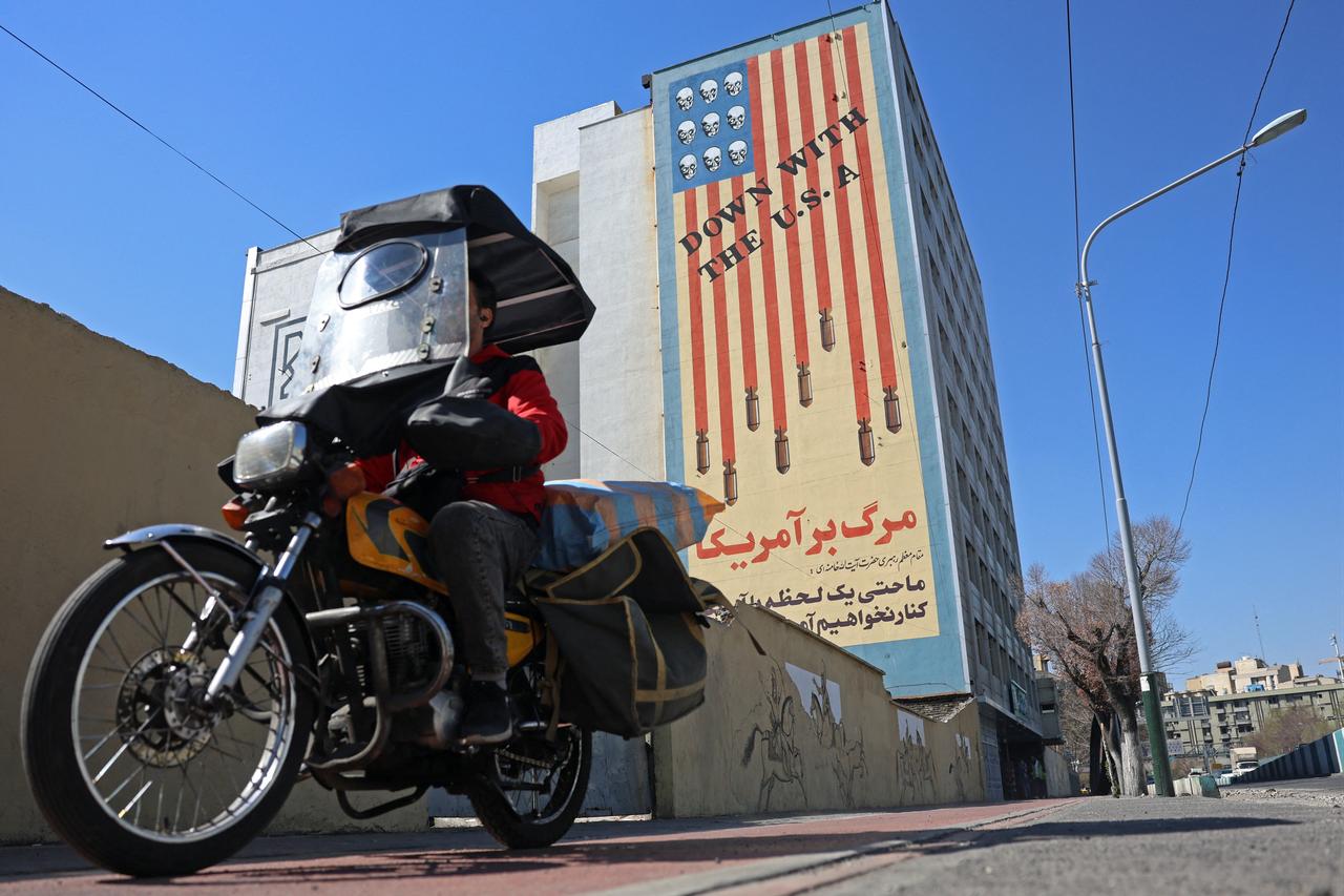 An Iranian man rides past an anti-US mural on a building in Tehran, Iran on February 26, 2026. (AFP Photo)