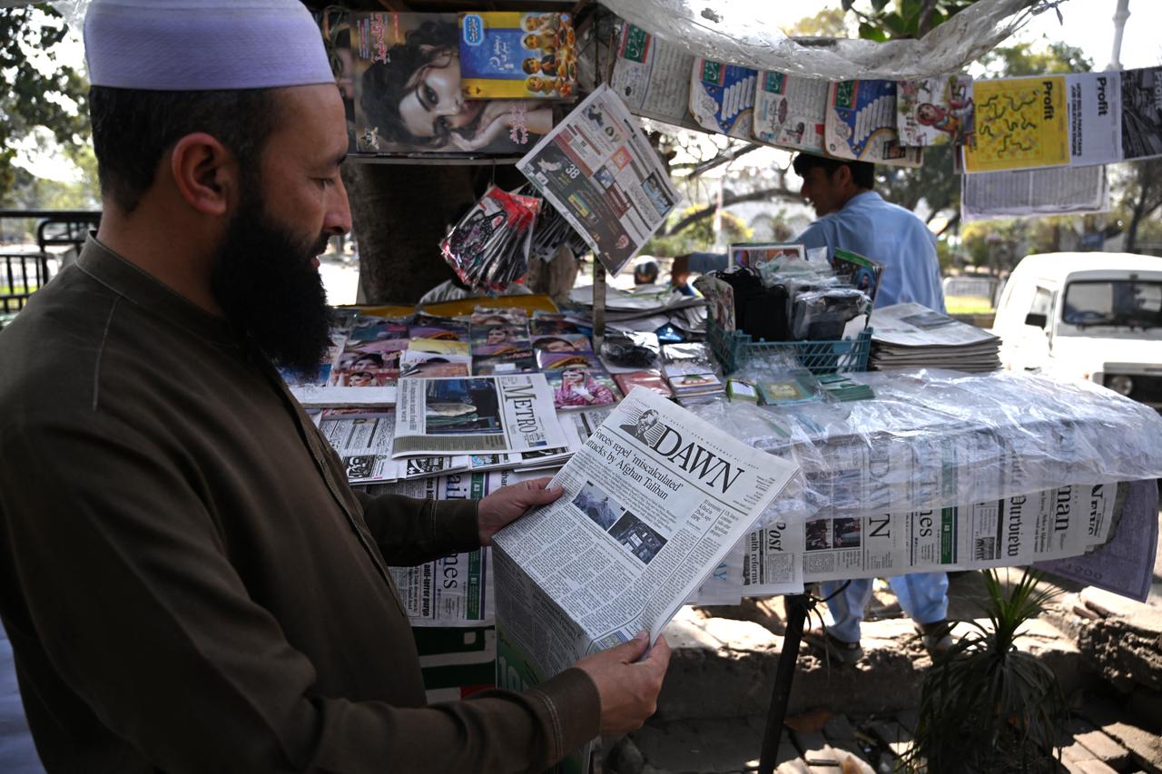 A man reads a newspaper reporting on the cross-border clashes between Pakistan and Afghanistan at a roadside stall in Islamabad on February 27, 2026. (AFP Photo)