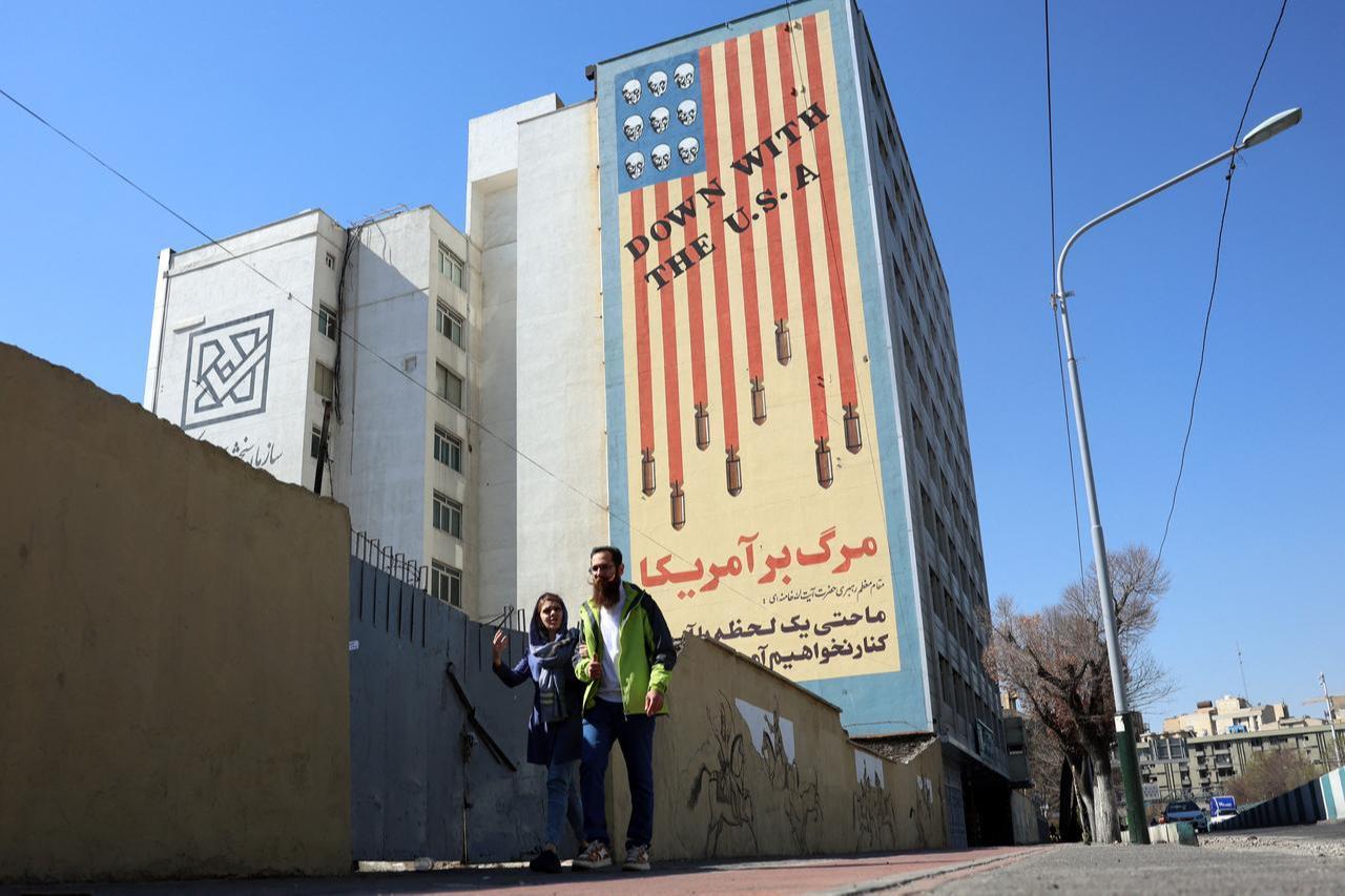 An Iranian couple walks past an anti-US mural on a building in Tehran on February 26, 2026. (AFP Photo)
