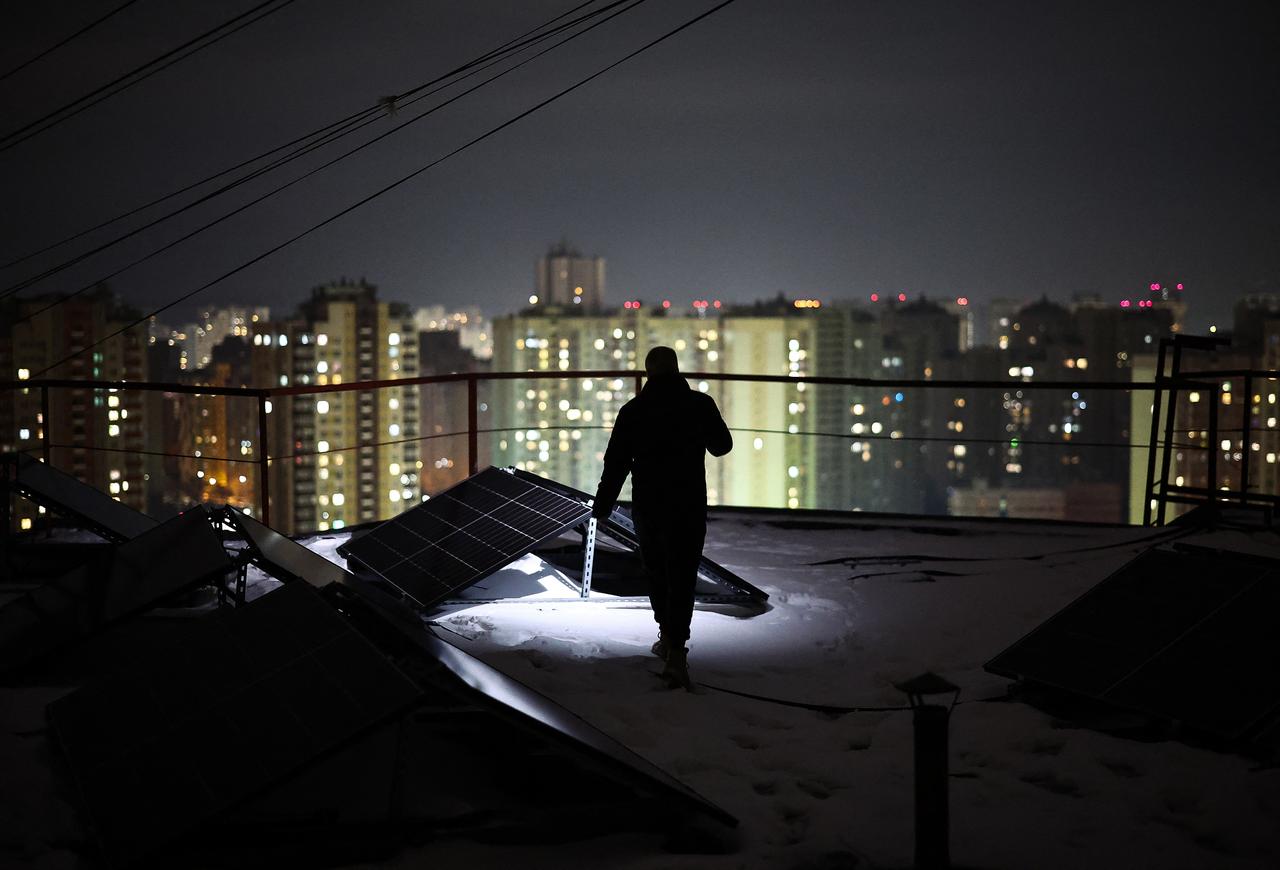 Chairman of the Board of the Association of Co-Owners of the Apartment Building 'Dzherelo' Denys Biletsky, 42, inspects solar panels on the rooftop of a residential building, which has been suffering from heating and power outages, in the Pozniaky district of Kyiv on February 22, 2026, amid the Russian invasion of Ukraine.  (AFP Photo)