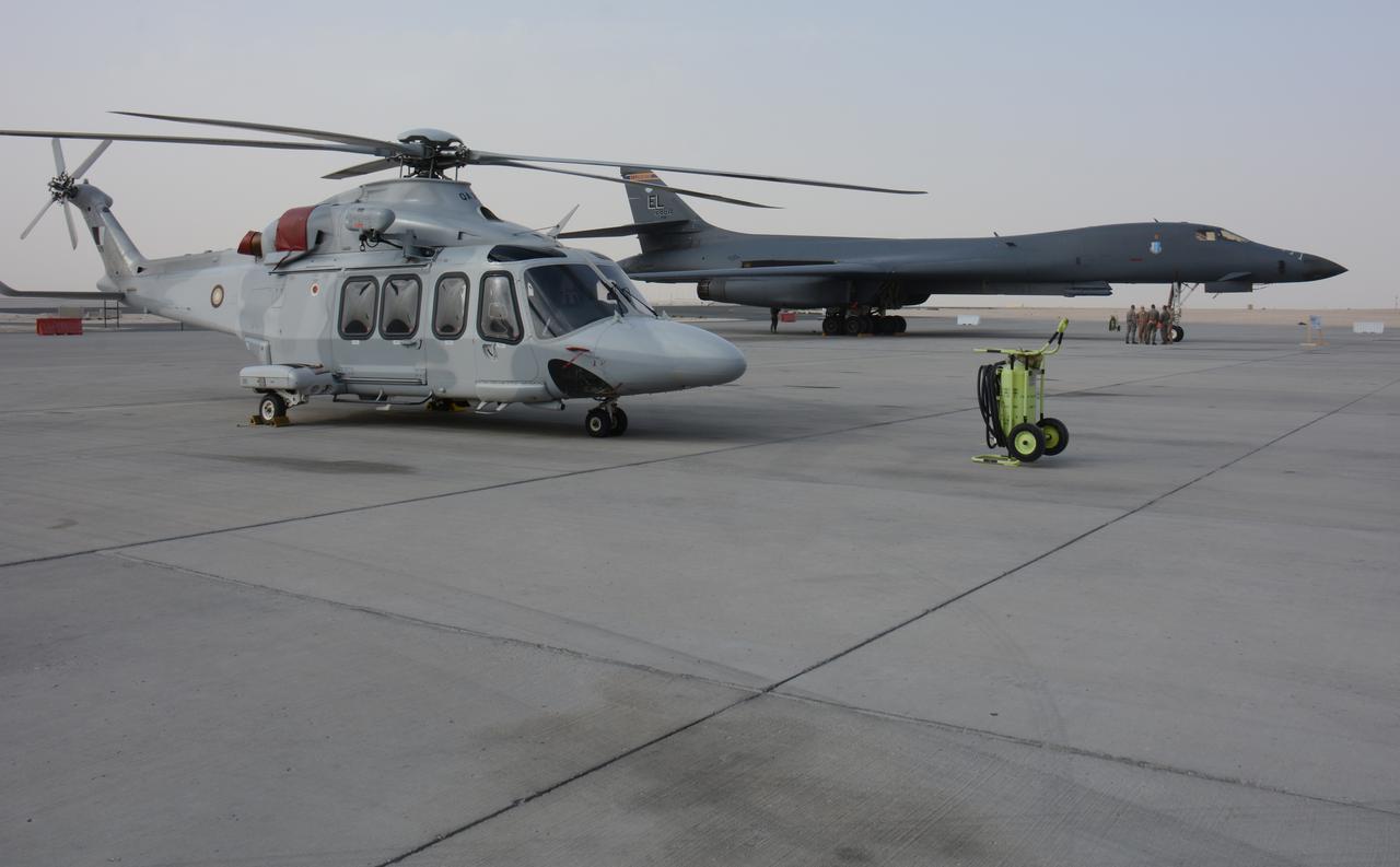 A Qatar Emiri Air Force helicopter and a U.S. Air Force B-1B Lancer wait for visitors at the annual Flight Line Fest Jan. 10 at Al Udeid Air Base, Qatar. (Photo via Wikimedia)