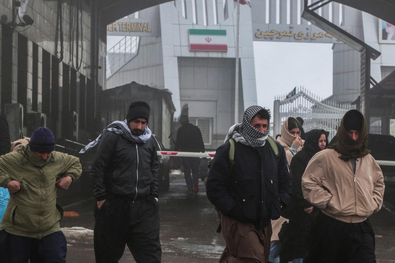 Travellers arrive at the Haji Omran border crossing with Iran (Iranian flag in the background), in Iraq's autonomous northern Kurdish region, which is open to travellers and economic trade on Feb. 1, 2026. (AFP Photo)