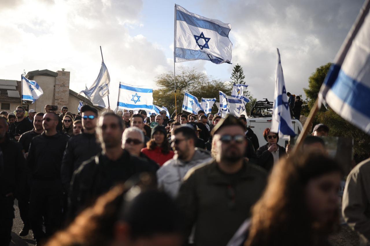 People wave Israeli flags as they walk towards the cemetery during the funeral of Israeli hostage Ran Gvili in the southern town of Meitar, January 28, 2026. (AFP Photo)