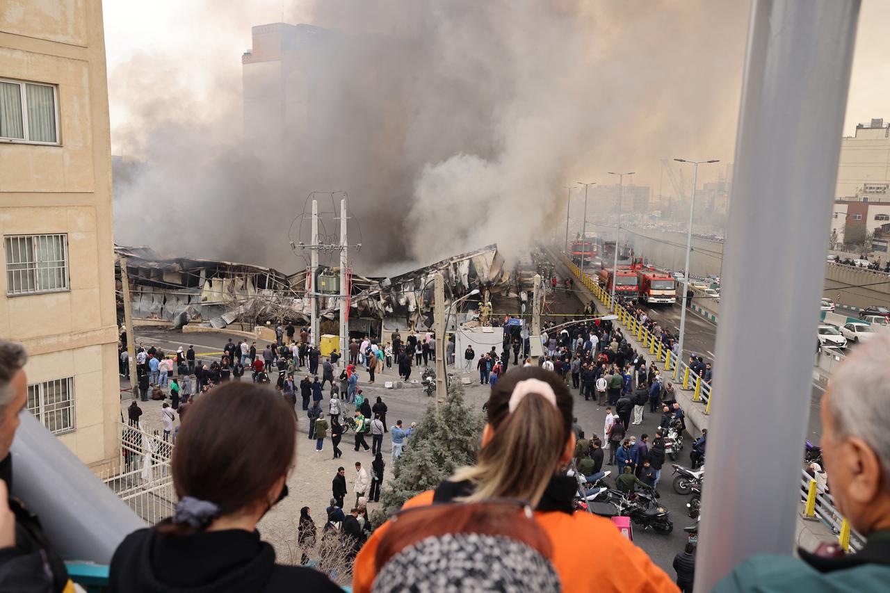 People stand and watch as smoke billow from a fire that broke out in Jannat Bazaar, west of Tehran, Iran on February 3, 2026. (AFP Photo)