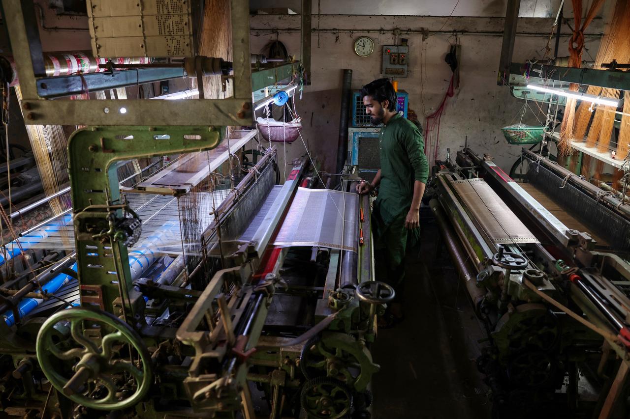 A worker weaves sarees and dress material on power looms at a workshop in Varanasi on February 1, 2026. (AFP Photo)