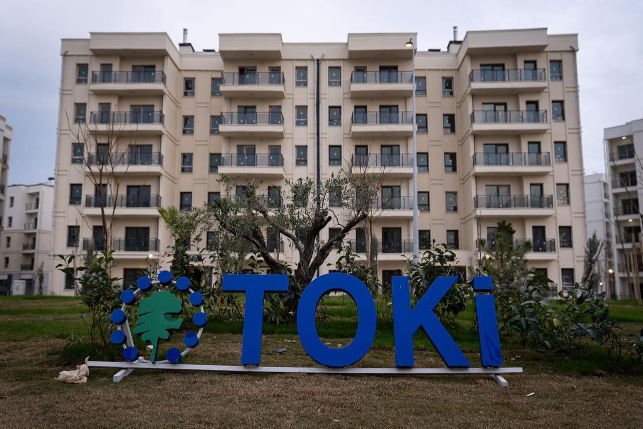 A TOKI sign, belonging to Türkiye’s state-run housing development administration, stands in front of newly completed social housing apartments in Hatay, Türkiye, Feb. 6, 2026. (AA Photo)