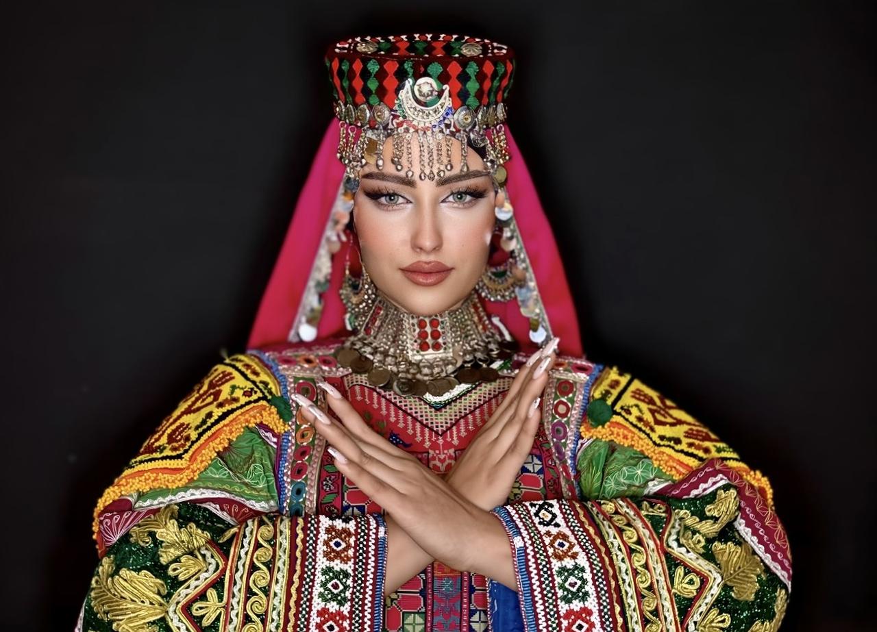 A woman wearing traditional Afghan attire performs the crossed-arm gesture associated with WomanPost’s global awareness campaign. (Courtesy of WomanPost)