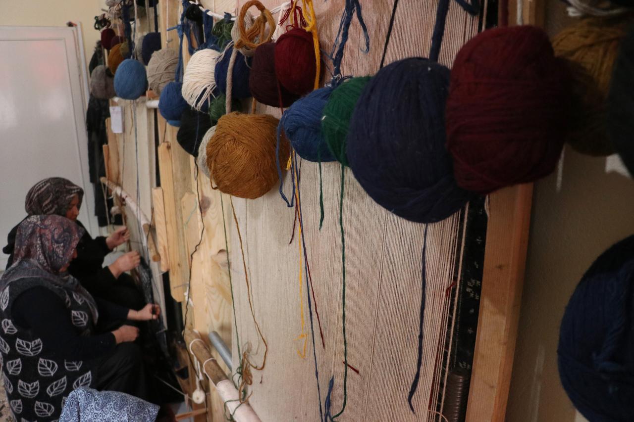 Yarn balls hang from wooden looms as women work on hand-woven carpets in Yahyali, Kayseri, central Türkiye, Feb. 7, 2026. (AA Photo)
