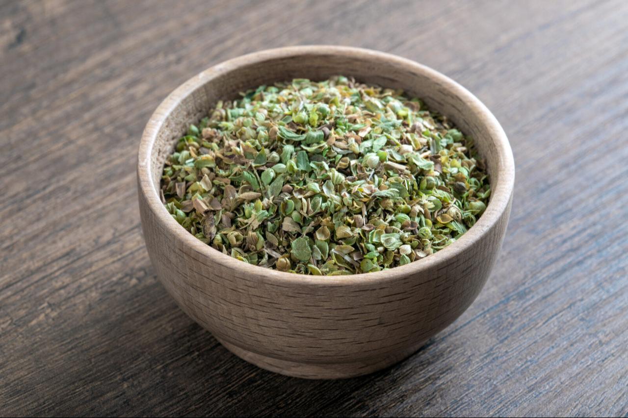 A bowl full of dried and ground organic mountain oregano on a wooden table. (Photo via Wide Angle)