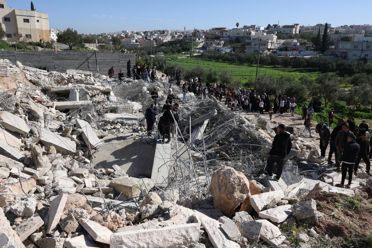 Palestinians gather to look at the concrete and steel debris from homes and shops after bulldozers protected by Israeli security forces demolished the buildings belonging to Palestinian families in Beit Aawa, West Bank on February 5, 2026. (AFP Photo)