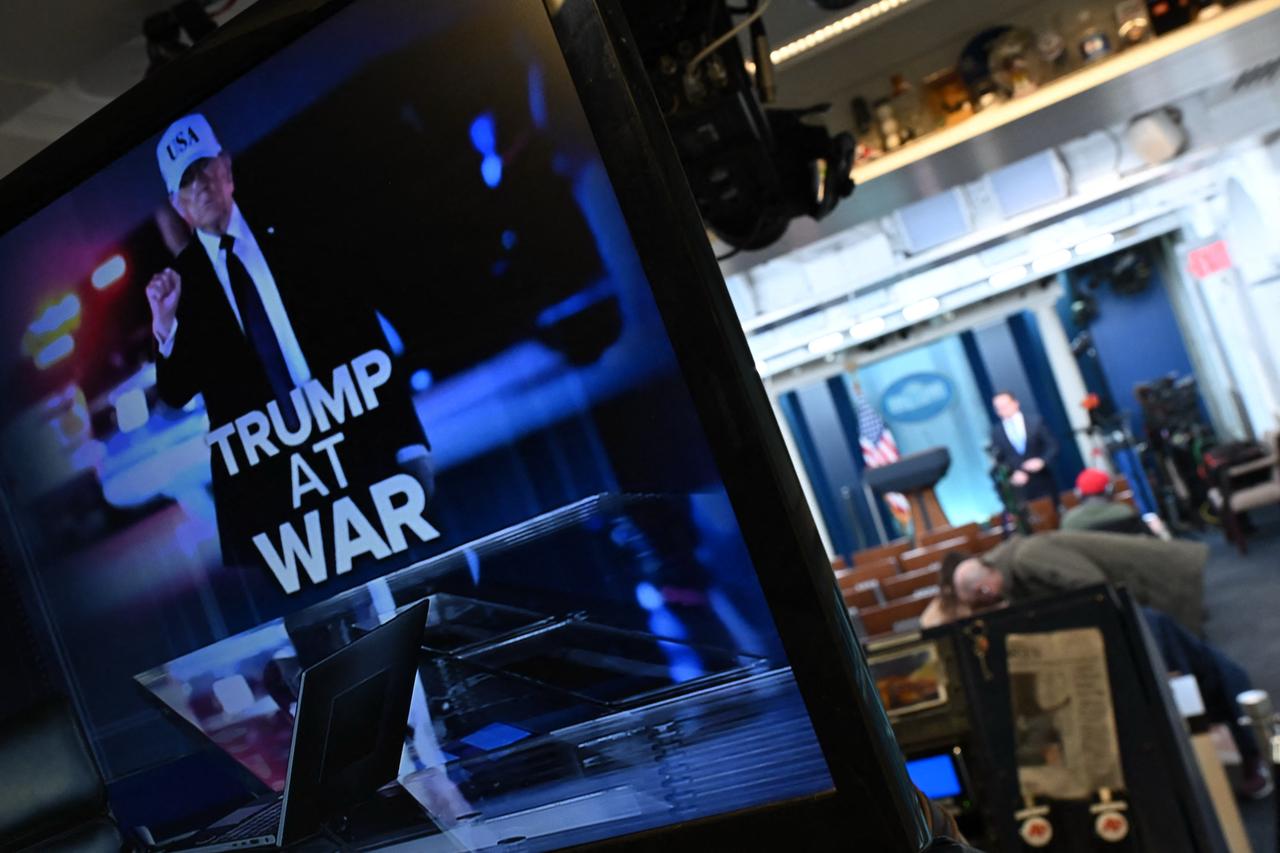 Reporters are seen in the briefing room near a television monitor displaying an illustration reading “Trump at War” alongside a photo of US President Donald Trump at the White House in Washington, DC, Feb. 28, 2026. (AFP Photo)